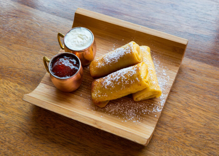 Three golden cheese blintzes with jam and sour cream at LOX at Cafe Bergson.